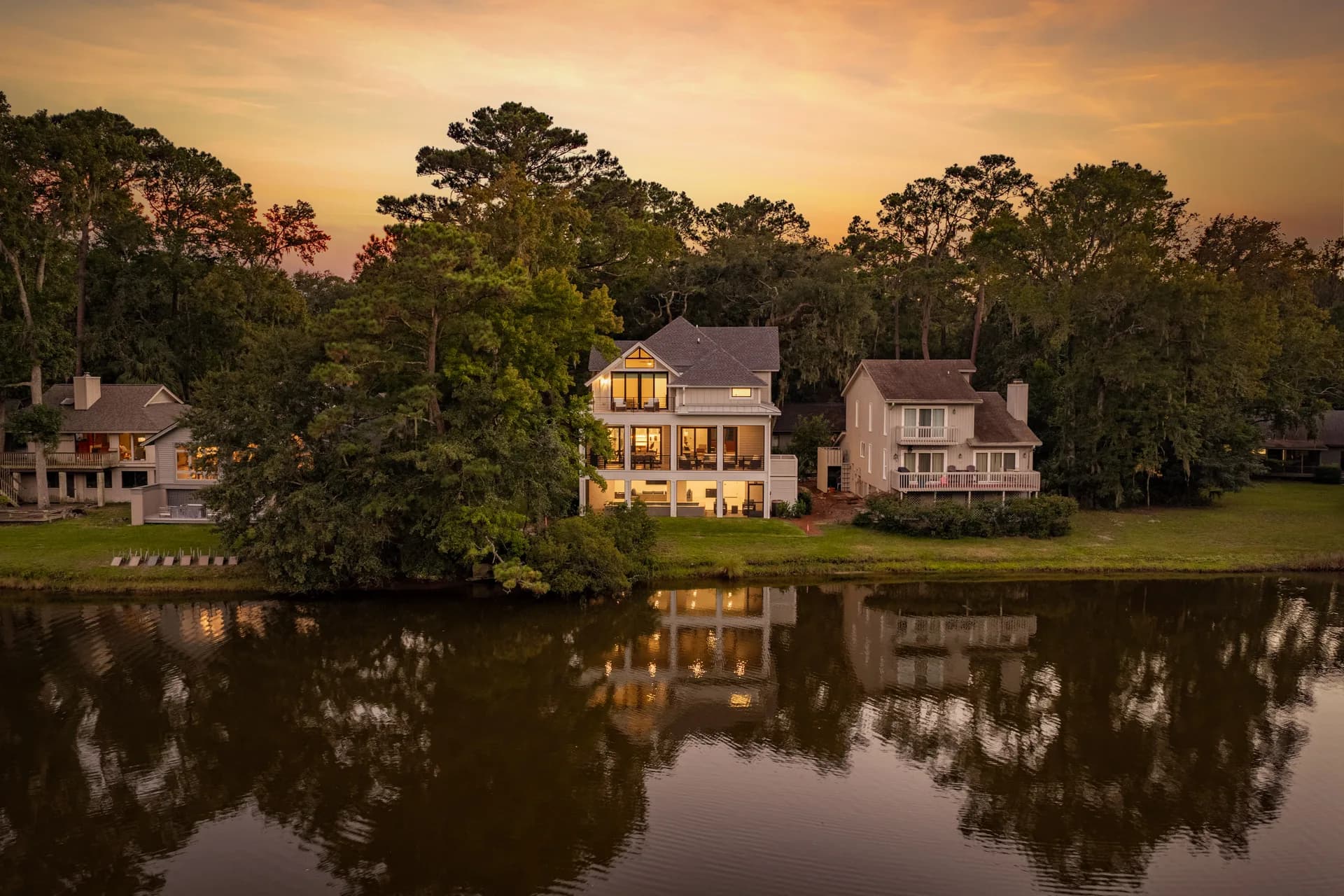 Illuminated rear exterior reflected in the lagoon beneath a sunset sky at 16 Indigo Lane