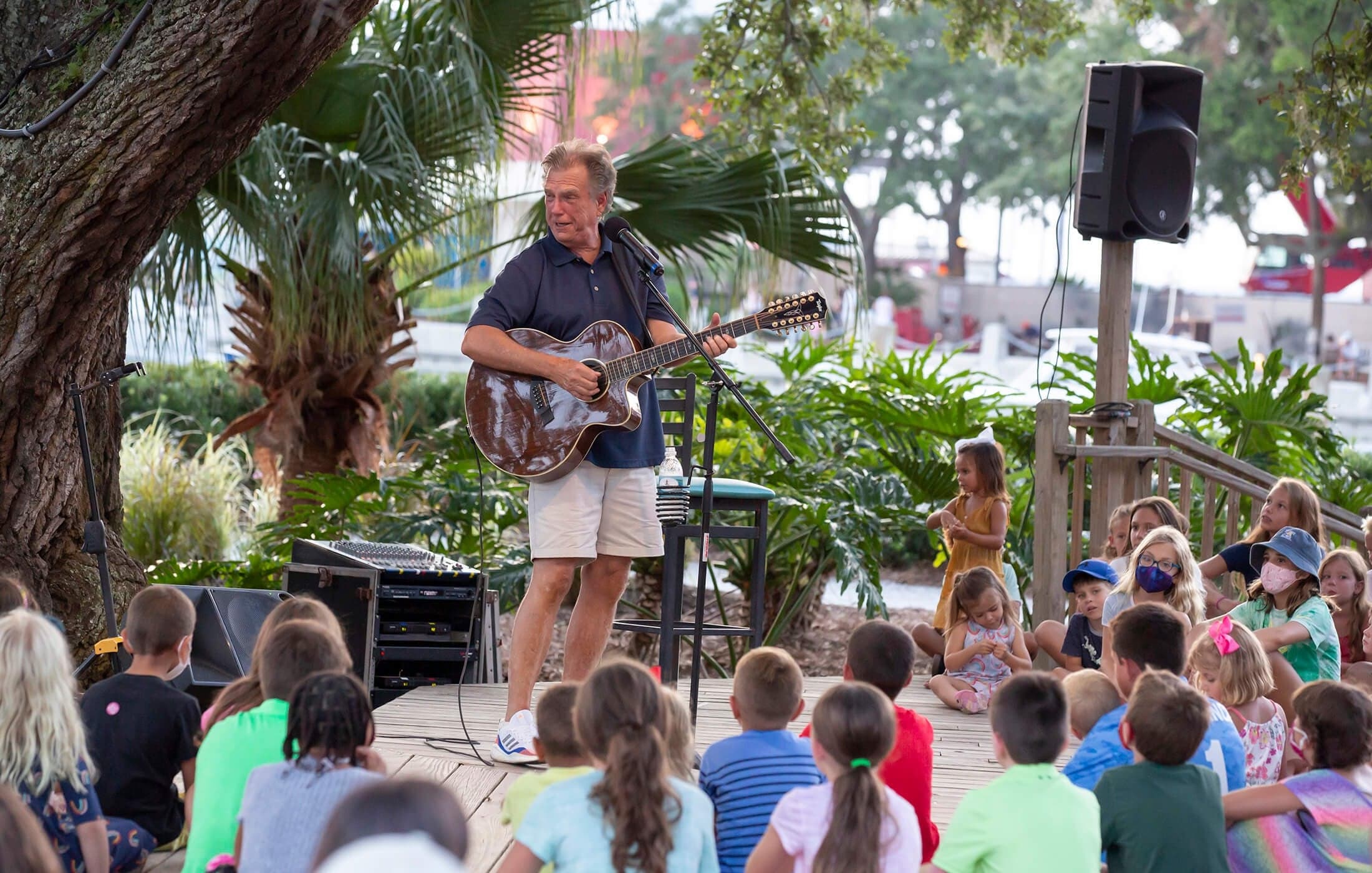 Children gathered for a family music performance beneath the trees in Harbour Town